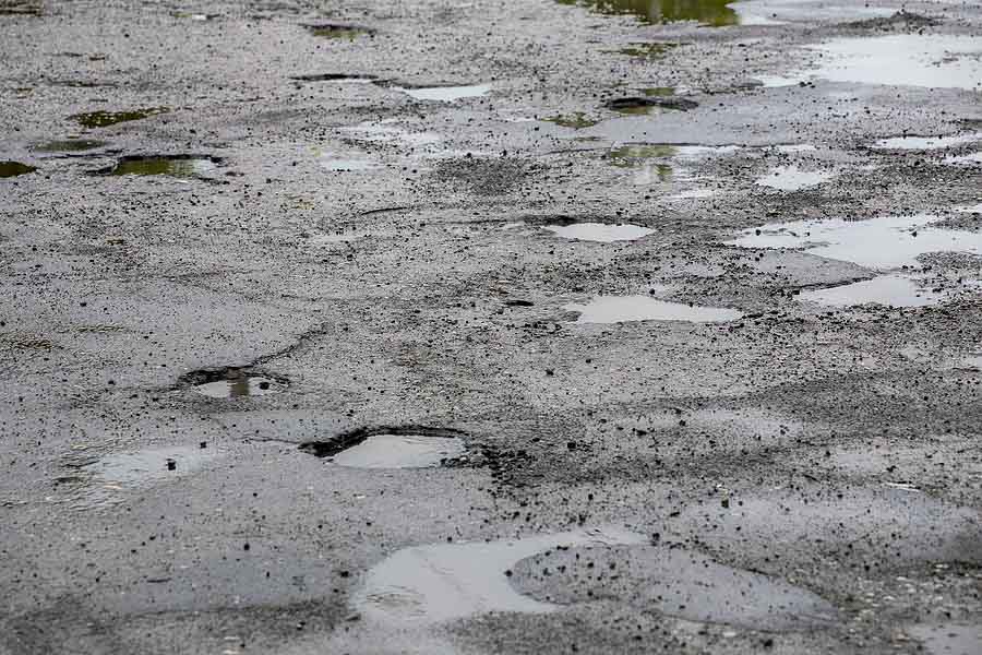 Bumpy Damaged Road Asphalt With Multiple Puddles After Rain At S