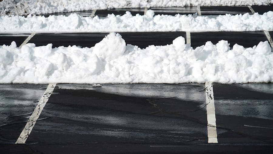 empty parking lot space with snow on the curb