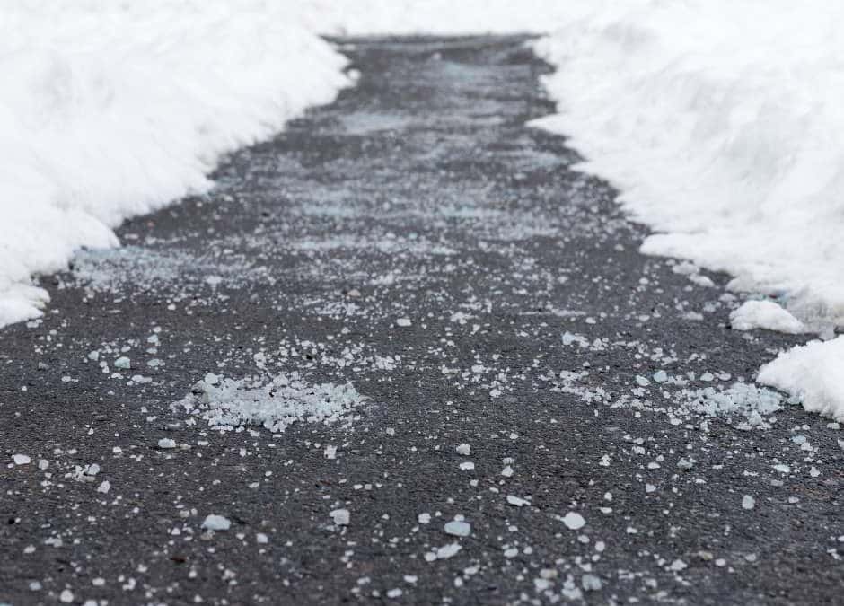 asphalt path cleared of snow with road salt on top